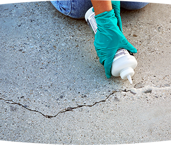 Person pouring Behr Premium Concrete Crack Filler into a crack